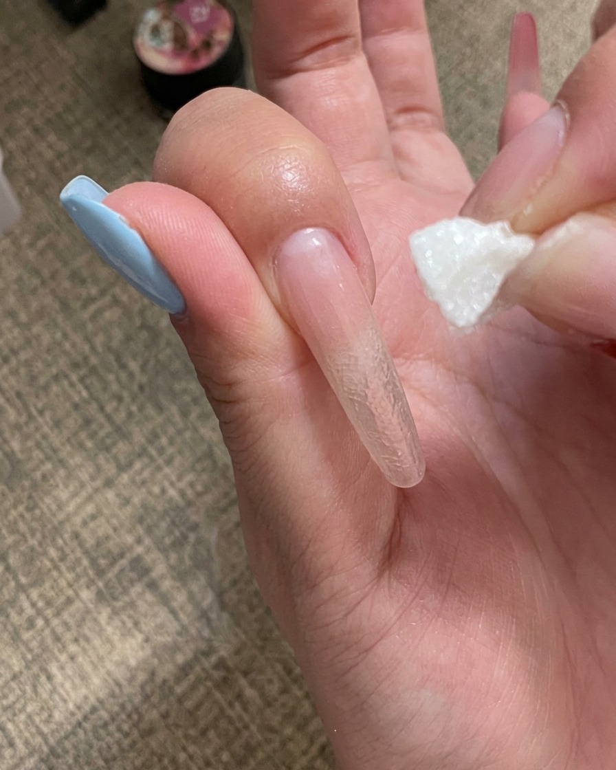 Una mano colocando una uña bajo una mini lámpara UV portátil.