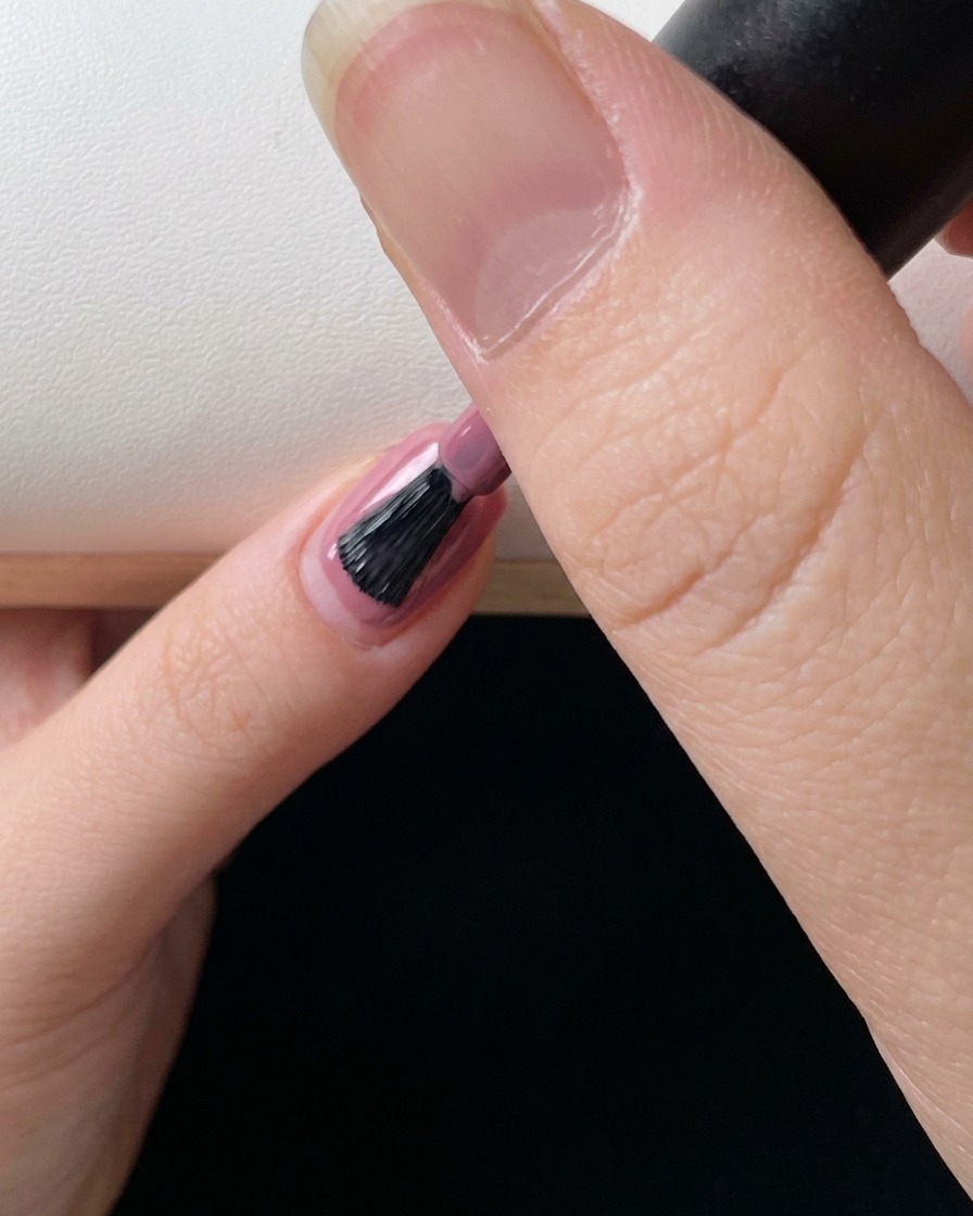 Primer plano de un pincel de uñas aplicando una capa final de gel rosa para perfeccionar el efecto degradado.