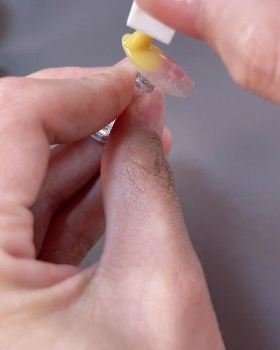 Una esponja aplicando gel amarillo brillante en el borde libre de la uña para crear un efecto degradado.