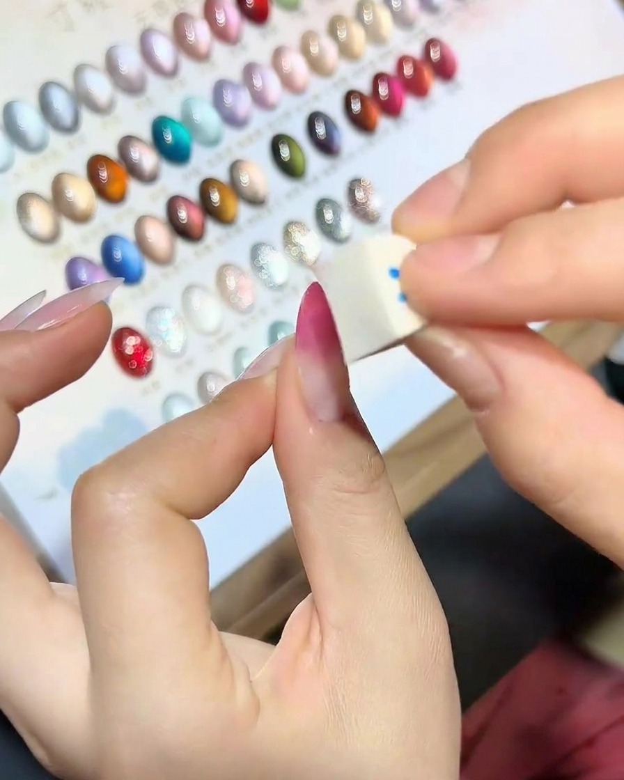 Un primer plano de la punta de una esponja impregnada con esmalte en gel magenta.
