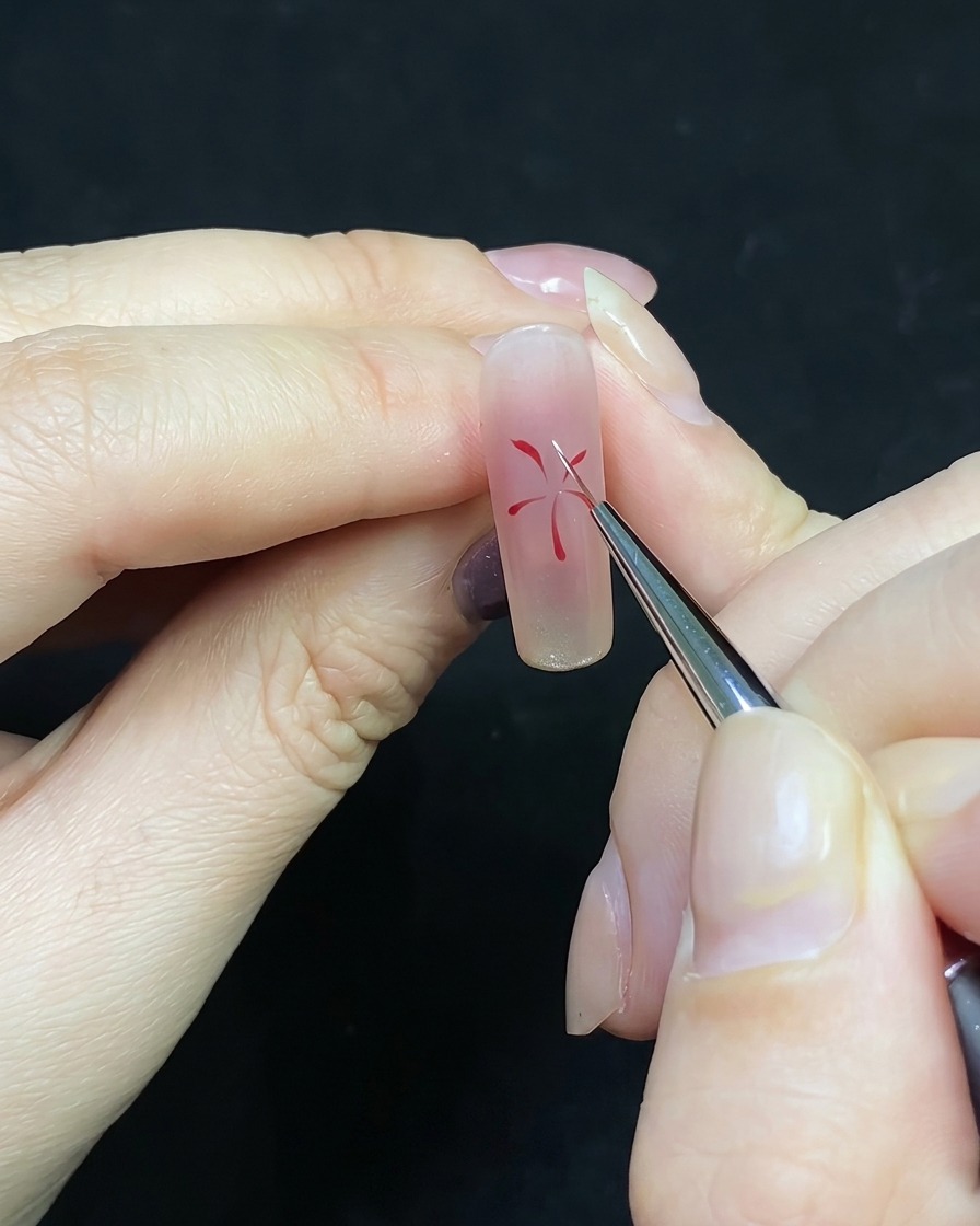 Un pincel de detalle añadiendo líneas blancas entre las líneas rojas existentes en un diseño de uñas.