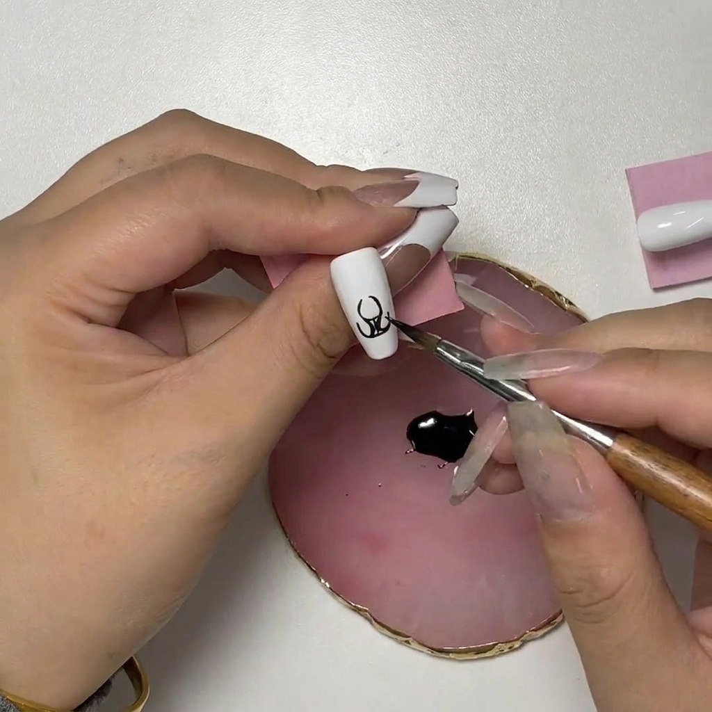 Primer plano del arte de uñas mostrando el pincel añadiendo trazos curvos ascendentes para formar las puntas.