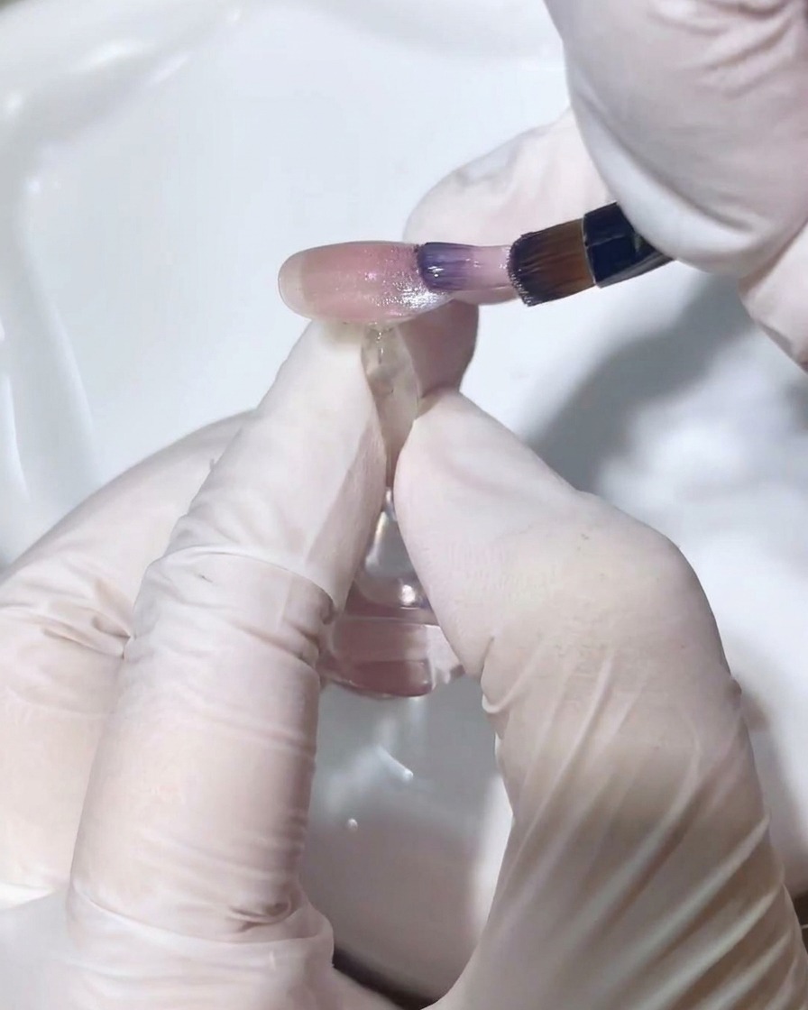 Un pincel de detalle difuminando delicadamente el esmalte cat-eye para crear un degradado fluido.