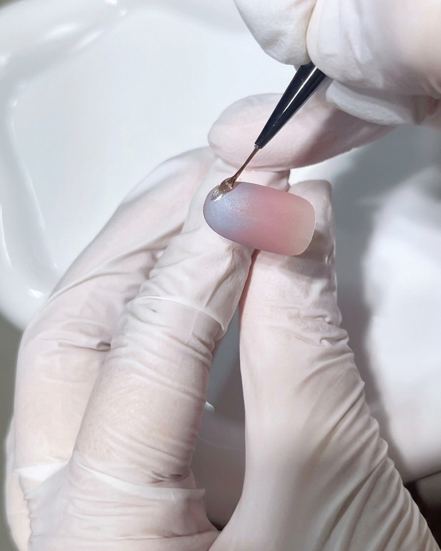 Vista de un pincel aplicando una gota precisa de gel denso sobre la uña para formar un relieve 3D.