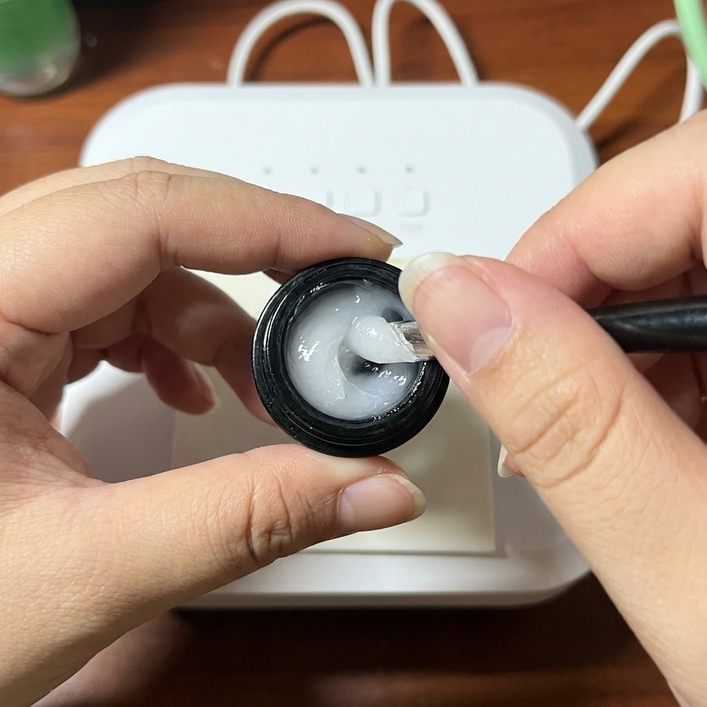 Primer plano de un pincel mezclando gel constructor y blooming gel en una paleta.