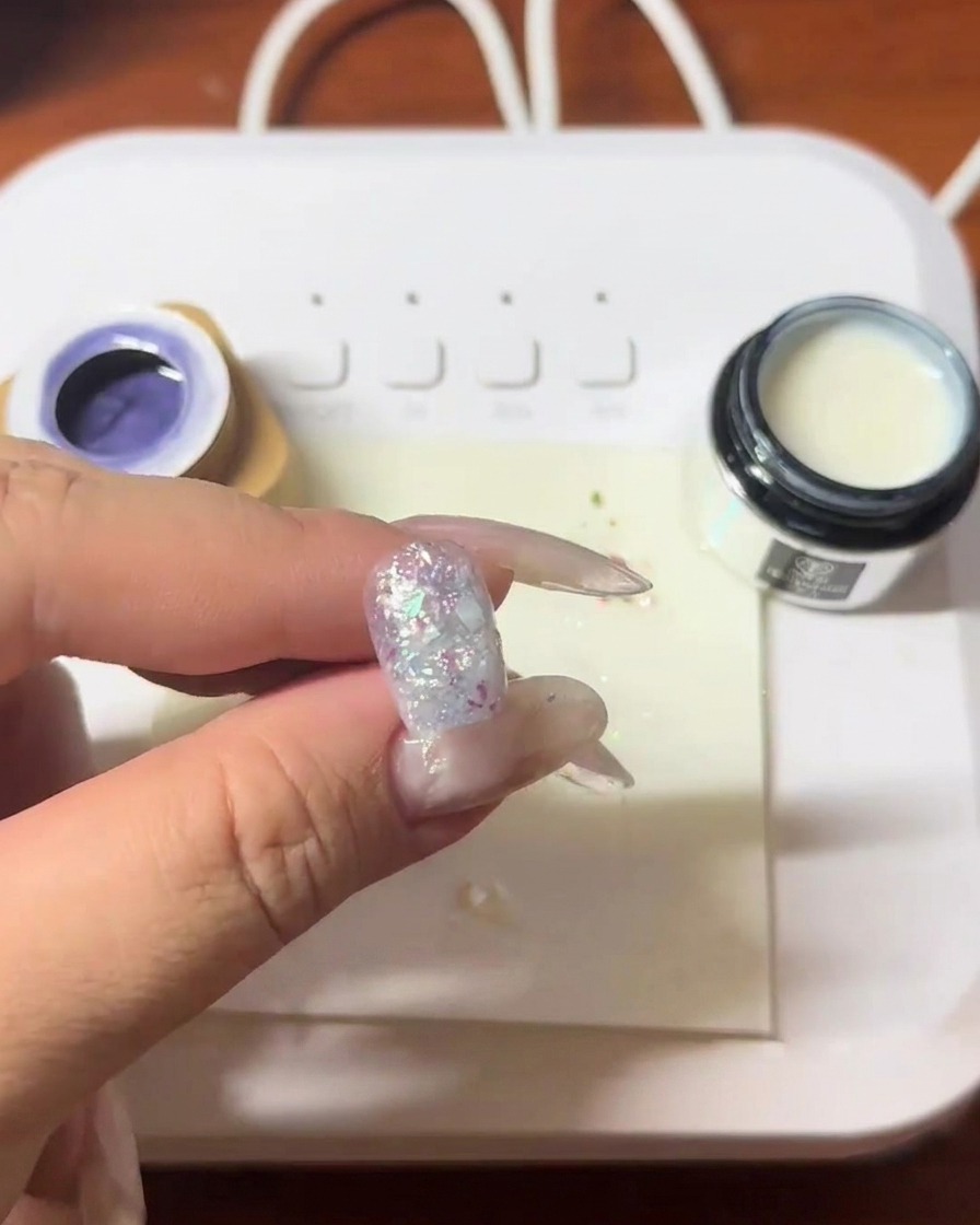 Una uña con fragmentos de concha siendo curada bajo una lámpara LED.
