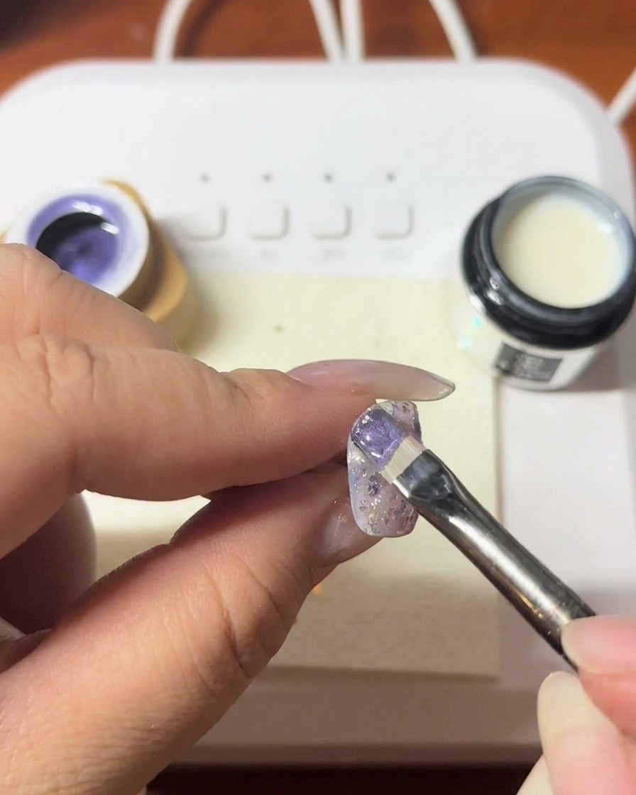 Imán siendo sostenido cerca de la uña para crear una línea brillante en el gel.
