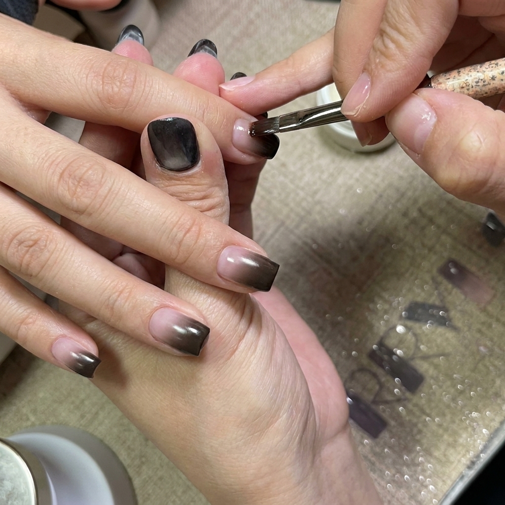 Un pincel de uñas aplicando una capa suave de gel transparente sobre las uñas con degradado.