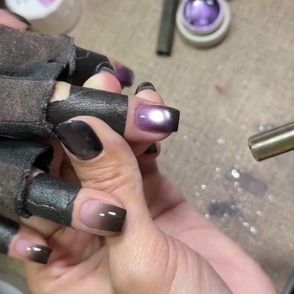 Uñas con gel cat eye morado curándose bajo una lámpara UV, con el brillo de la lámpara visible.