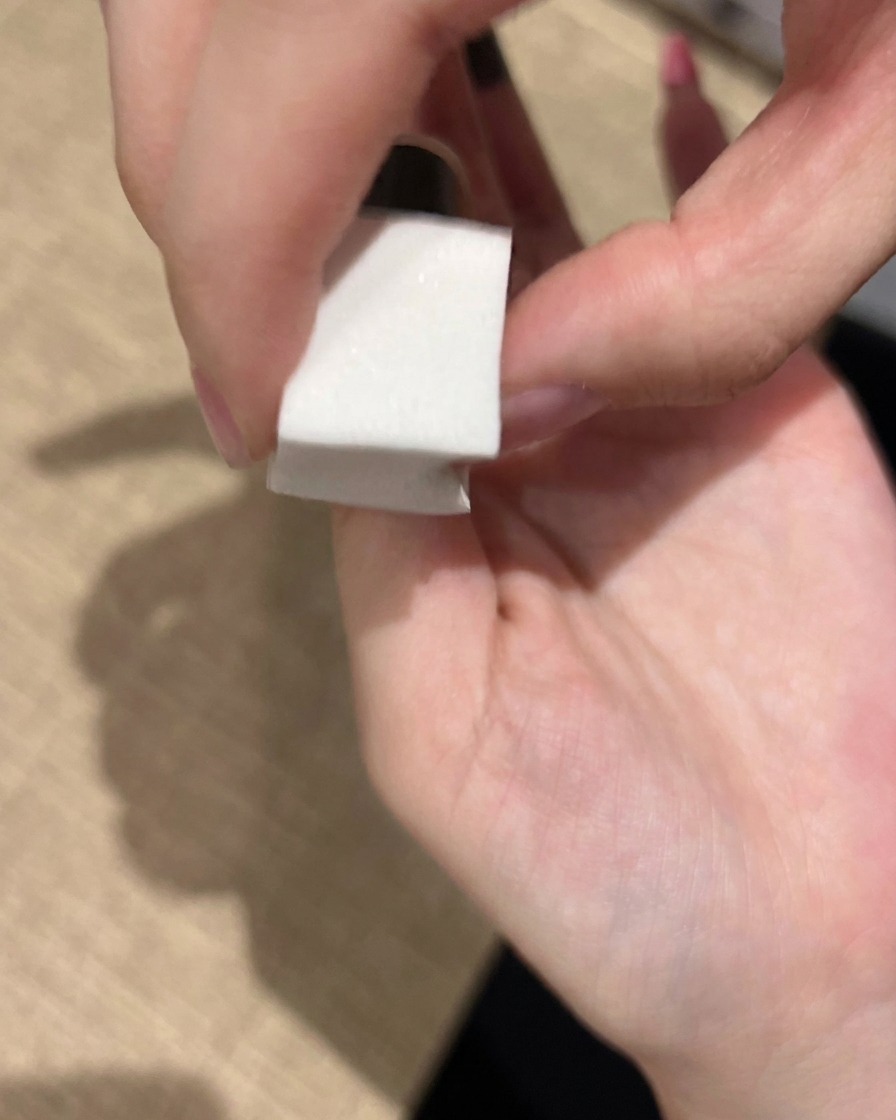 Una esponja de maquillaje siendo utilizada para aplicar suavemente esmalte de gel rosa sobre una uña para construir un degradado difuminado.