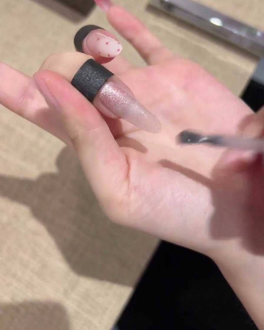 Un pincel aplicando un esmalte de gel ojo de gato brillante uniformemente a lo largo de toda la uña.