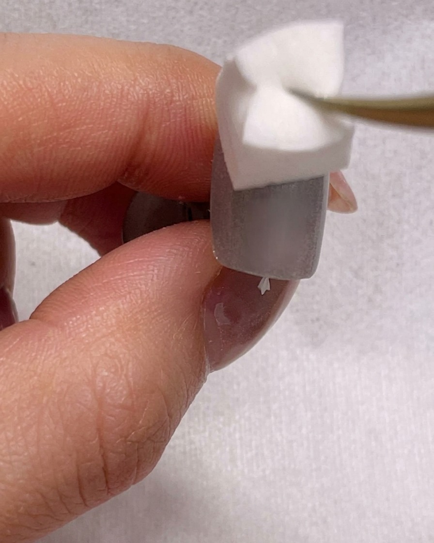 Vista en primer plano de una esponja difuminando esmalte azul sobre una uña para crear un efecto ombré.