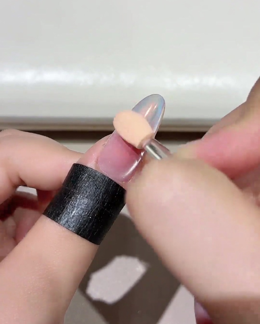 Un primer plano de una uña manicurada colocada dentro de una lámpara profesional UV/LED, mostrando el proceso de curado.