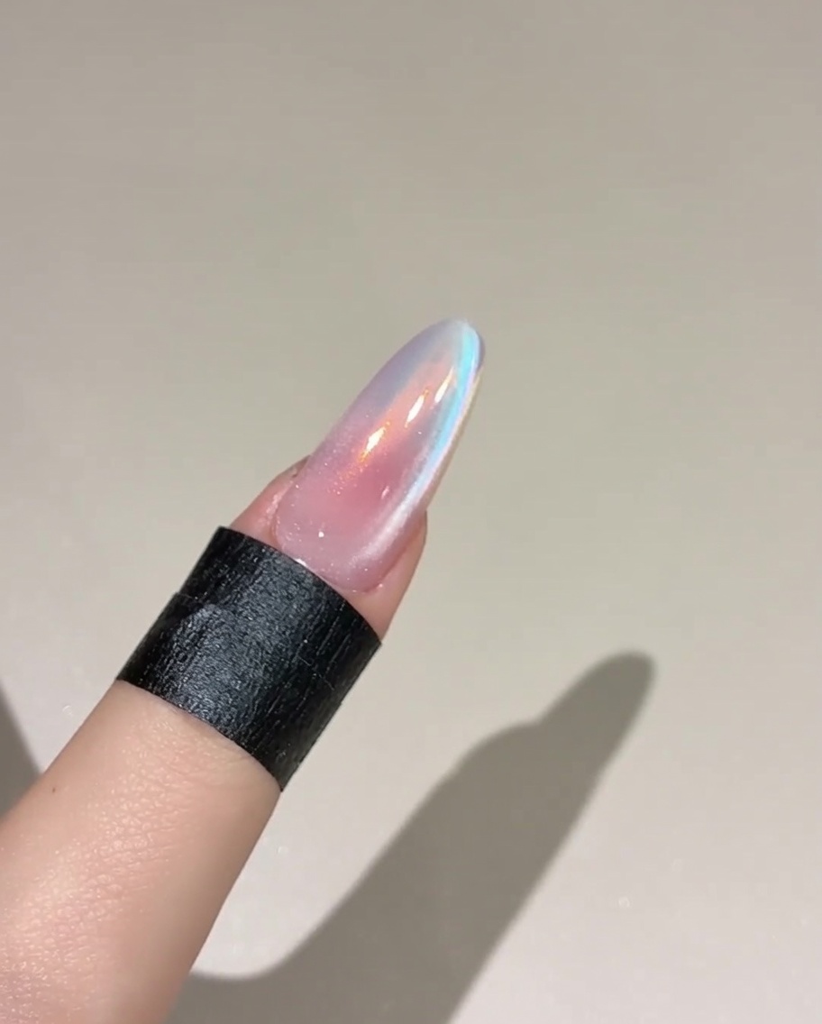 Un pincel aplicando una capa de gel top coat sobre una uña rosada curada.