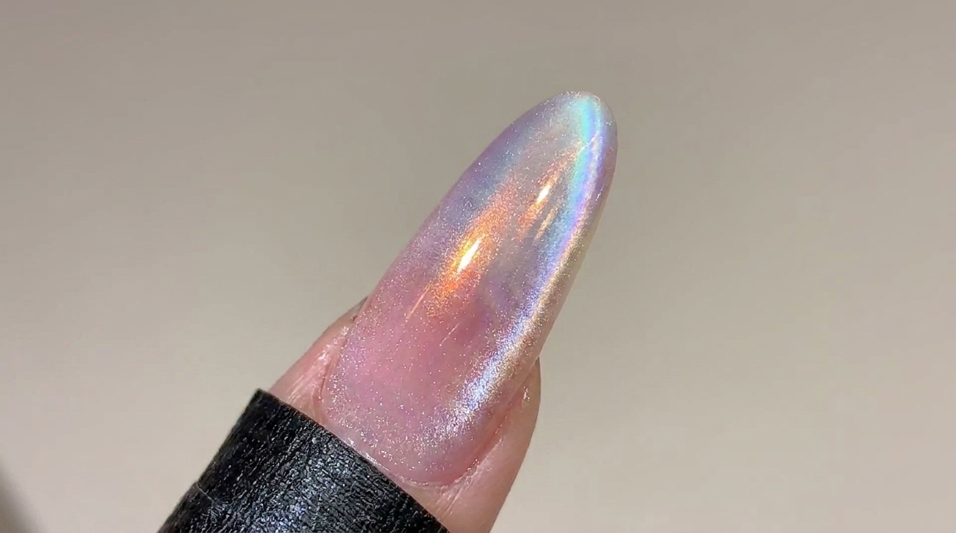 Una uña larga con forma almendrada que muestra un suave degradado de rosa a aurora con un sutil y brillante efecto magnético cat eye.