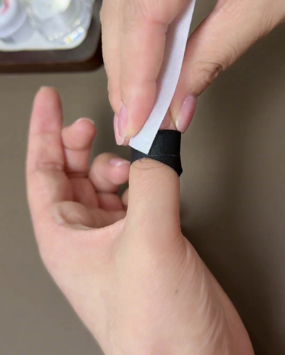 Una toallita sin pelusa utilizada para limpiar la superficie de una uña de gel curada.