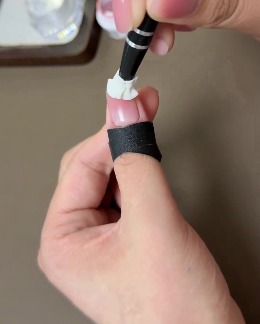 Una uña con efecto blush melocotón curándose dentro de una lámpara LED.