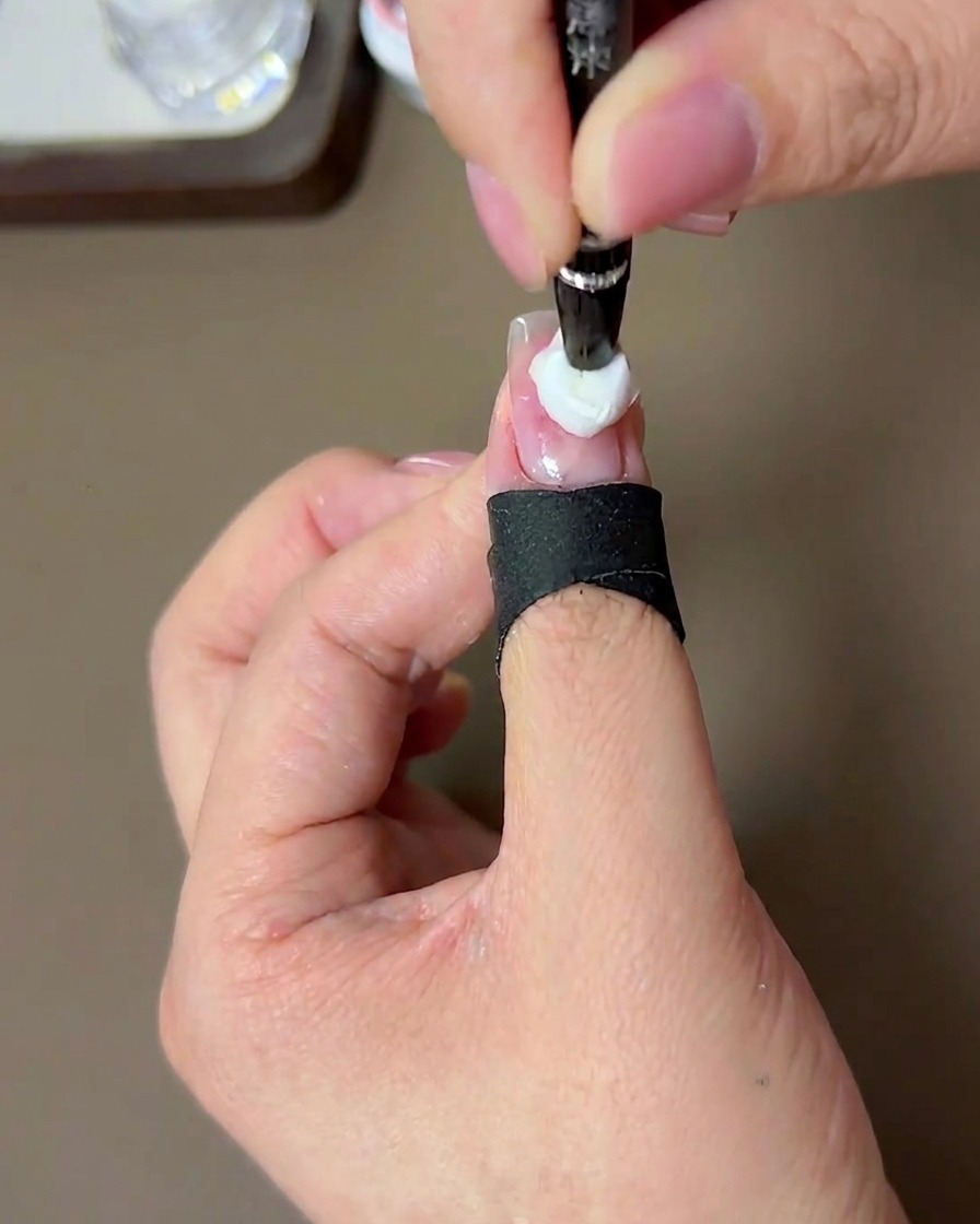 Un pincel aplicando una segunda gota más concentrada de gel melocotón sobre el centro de la capa anterior.