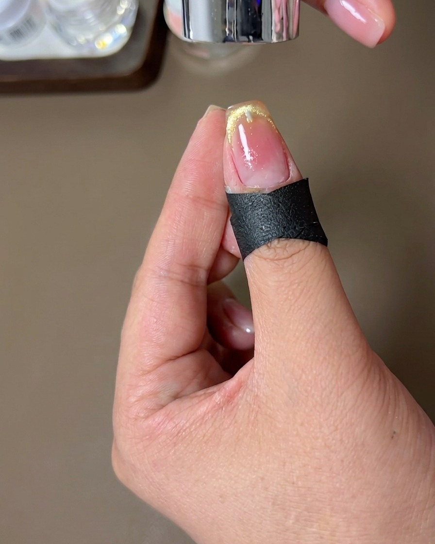 Una uña con el diseño terminado de punta francesa magnética curándose bajo una lámpara de uñas.