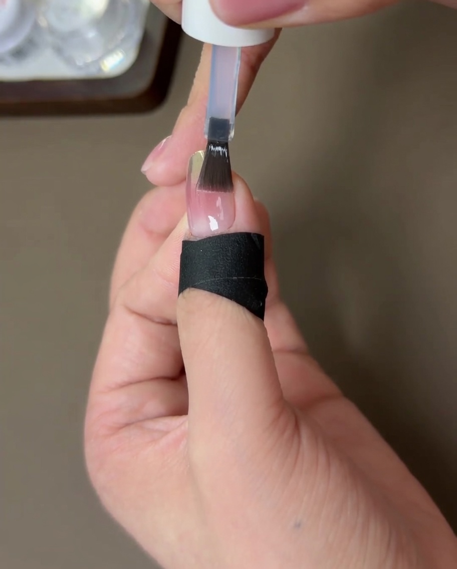 Una uña terminada con un top coat fortalecedor, curándose bajo una lámpara UV para uñas.