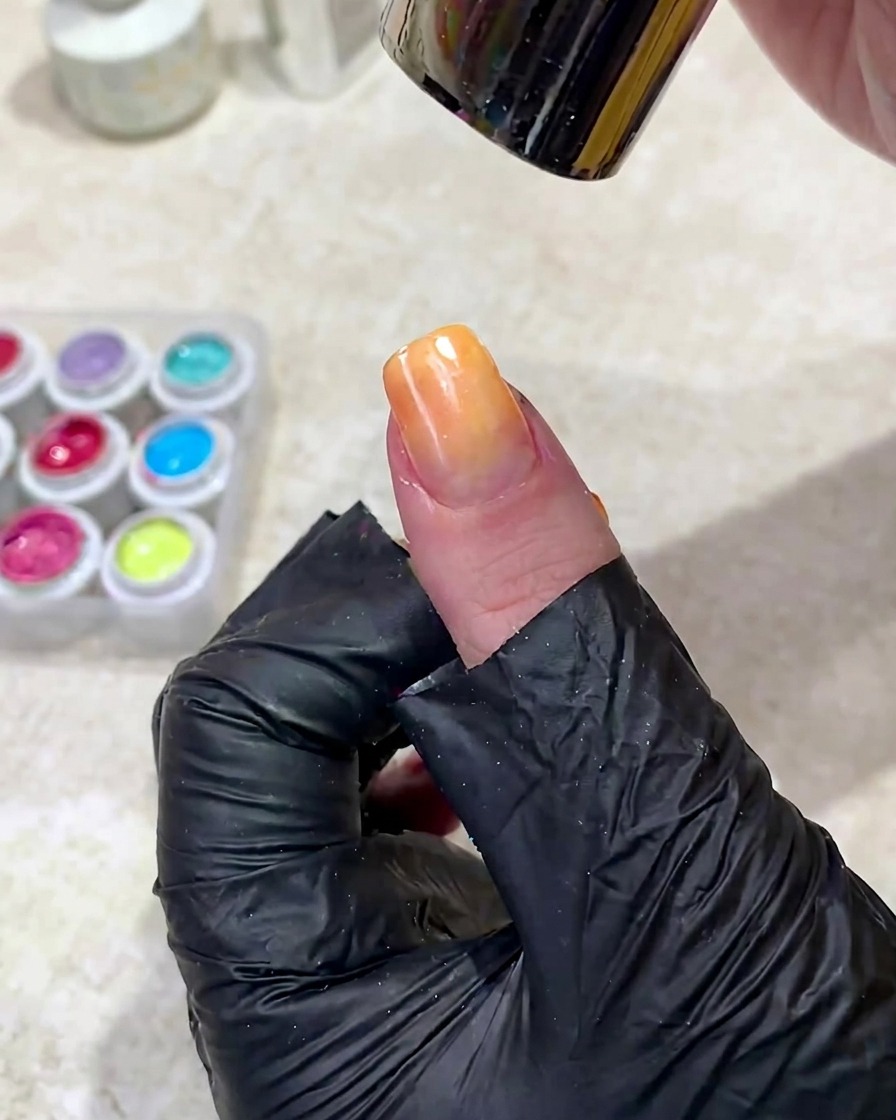 Una mano colocada bajo una lámpara de uñas UV para curar el gel degradado recién aplicado.