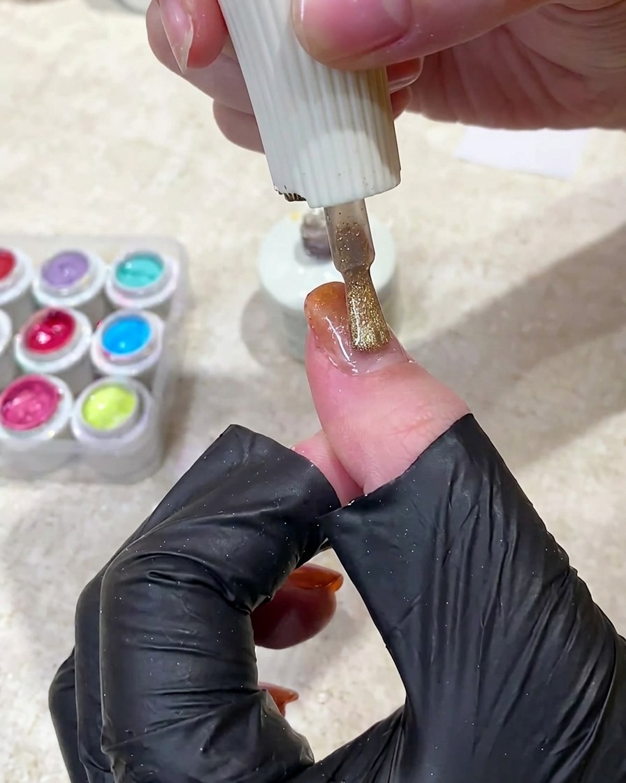 Un imán sostenido sobre una uña de gel húmedo para mover las partículas magnéticas hacia una franja brillante.