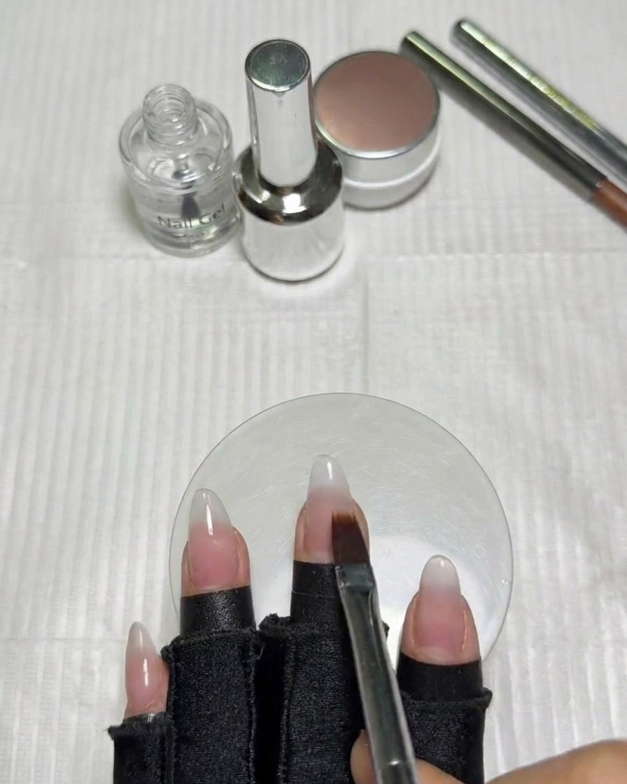 Una mano con uñas degradadas colocada dentro de una lámpara UV/LED para su curado.