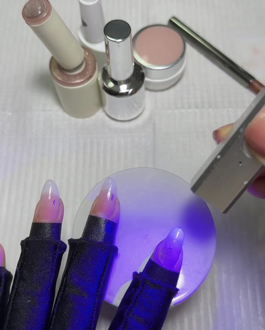 Uñas reposando bajo una lámpara UV y LED de luz violeta para curar la estrella ojo de gato recién activada.