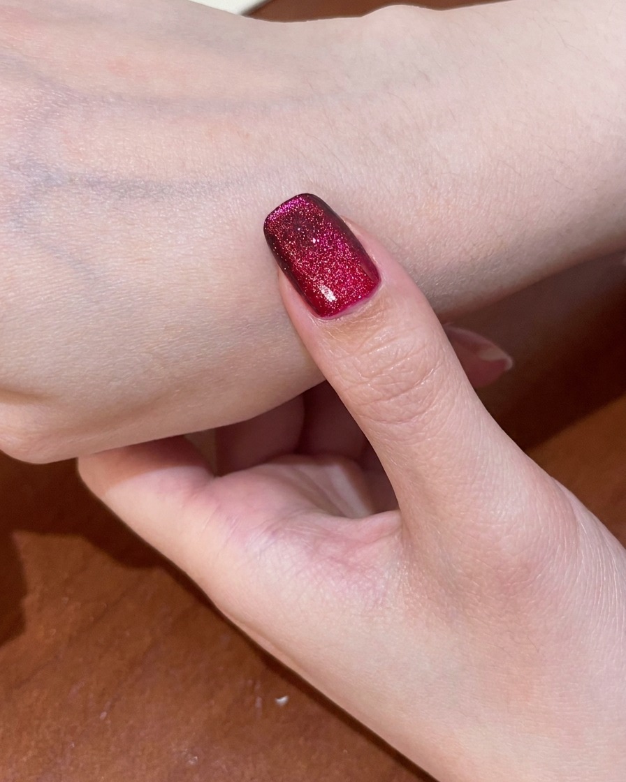 Una uña con el diseño cat-eye rojo completado siendo curada dentro de una lámpara UV.