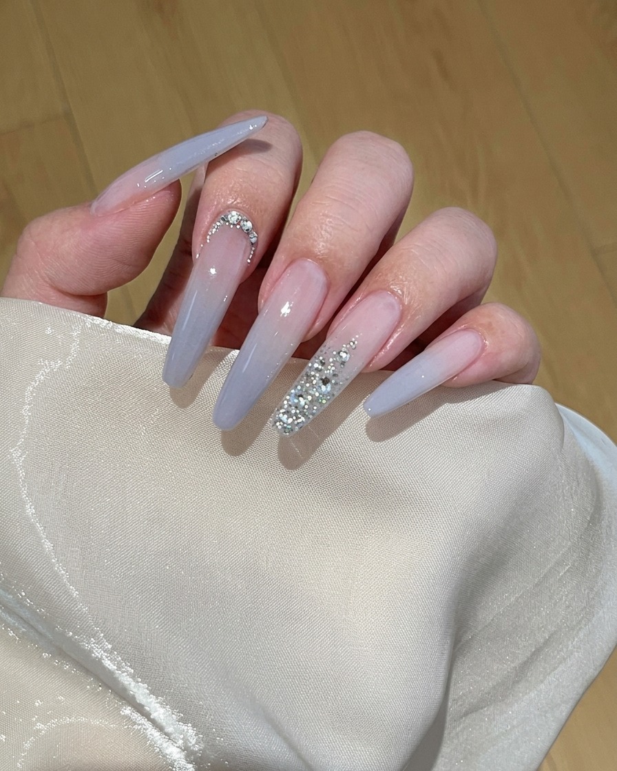 Un primer plano de un pincel aplicando esmalte en gel color melocotón claro sobre una uña natural.