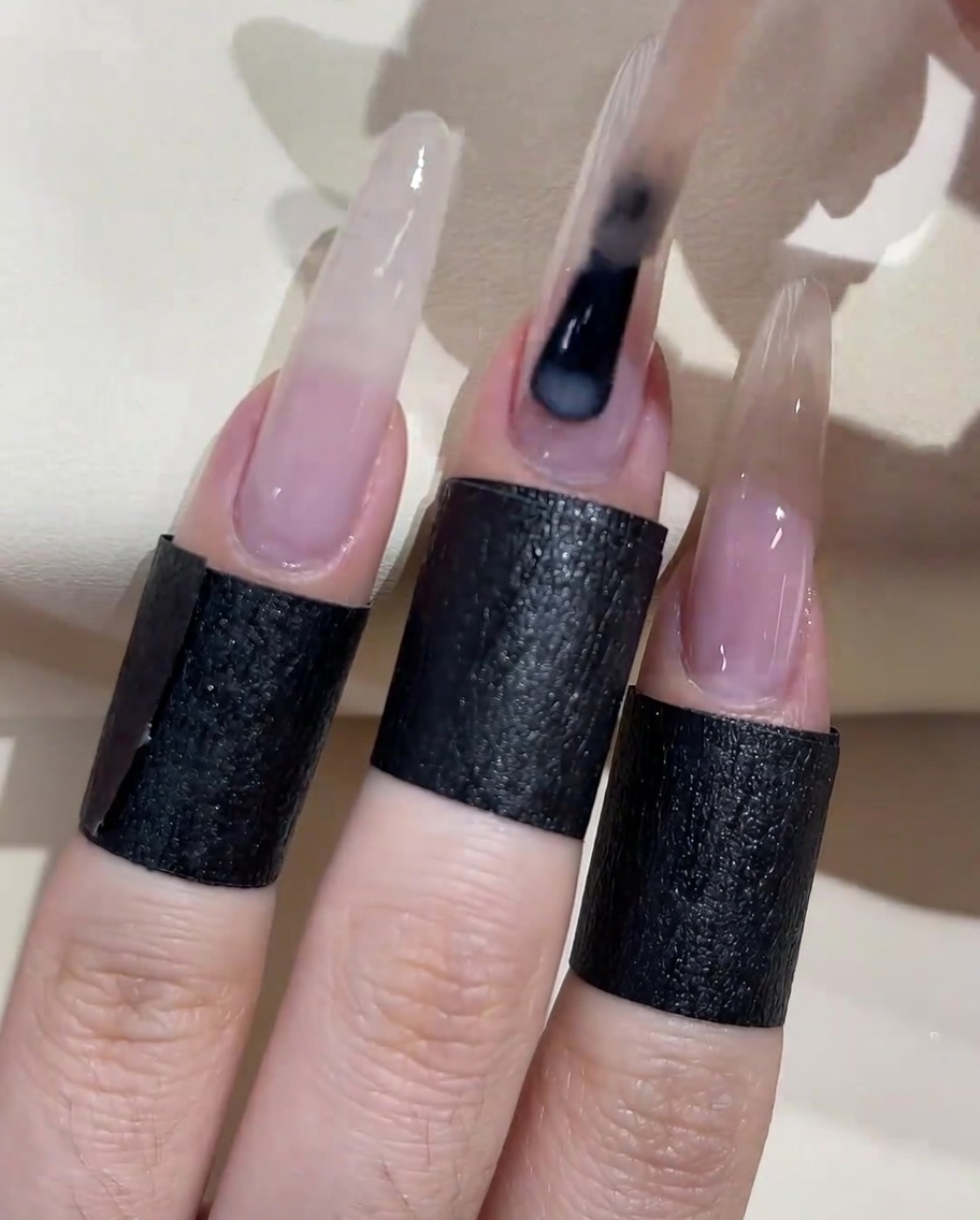 Un pincel aplicando una segunda capa de esmalte en gel melocotón lechoso sobre la superficie de la uña.