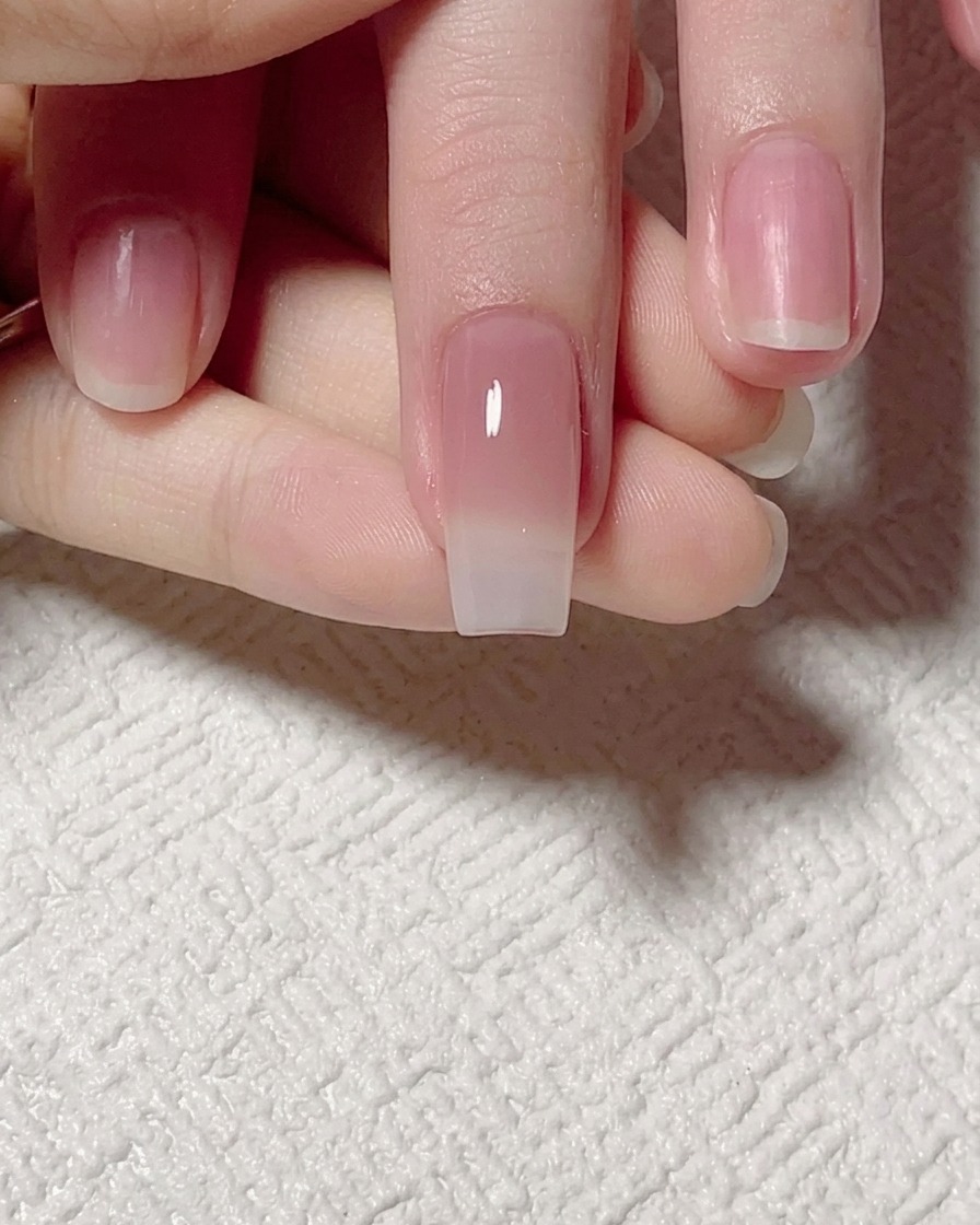 Un pincel plano difuminando el gel tono jade hacia arriba para crear una transición suave en la uña.