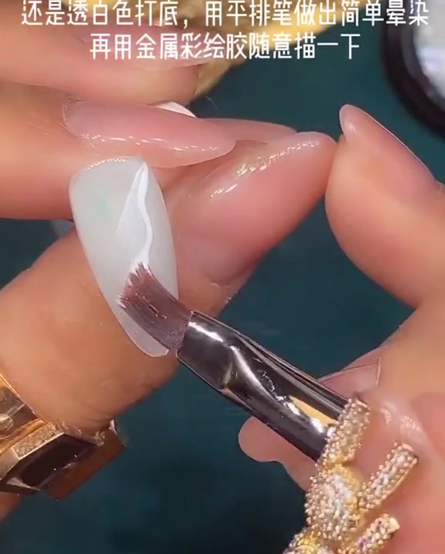 Un pincel plano siendo utilizado para difuminar esmalte de gel blanco húmedo sobre la uña.