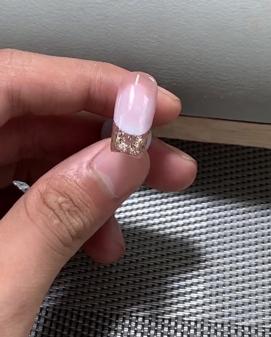 Una mano colocada bajo una lámpara UV profesional para curar el esmalte en gel.