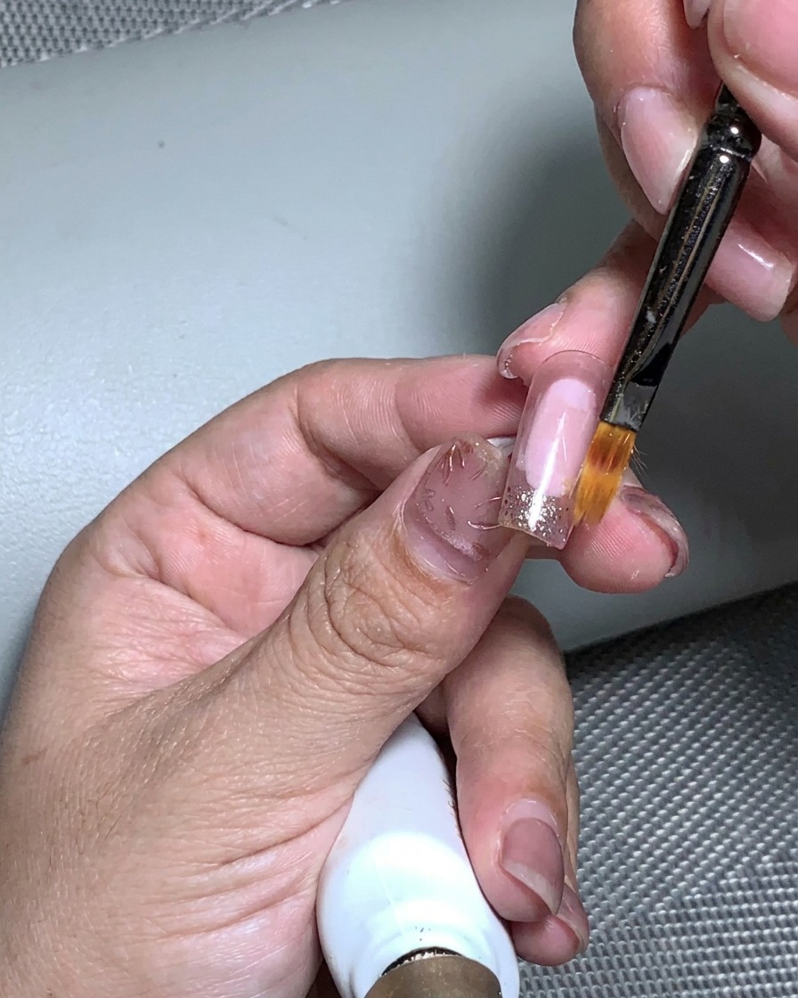 Una mano colocada dentro de una lámpara UV para curar la aplicación de pan de oro.