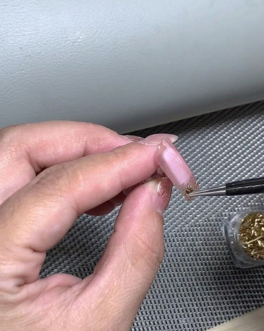 Un dedo presionando una pegatina de manicura francesa para asegurar su total adherencia a la uña.