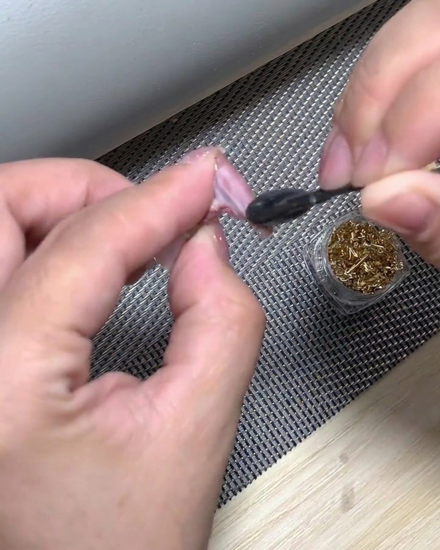 Una esponja de maquillaje aplicando esmalte blanco en la punta de la uña a toquecitos para crear una transición ombré.