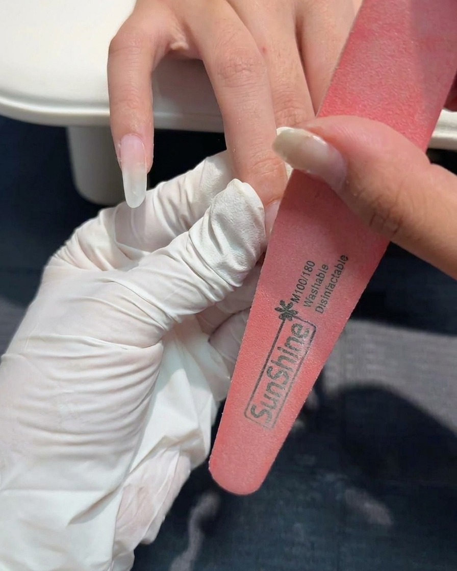 Una lima de uñas de mano refinando la superficie de una uña de gel estructurada.