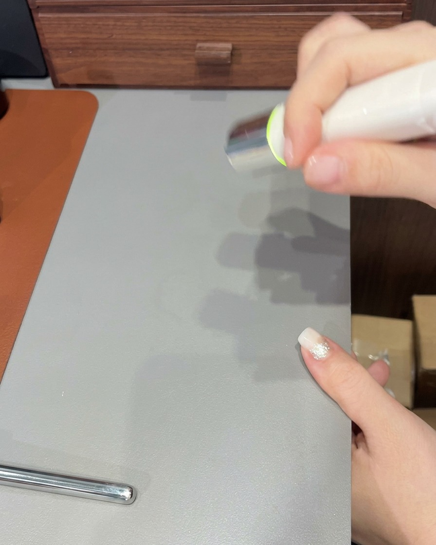 Un pincel de uñas aplicando una última capa transparente de gel sobre una uña terminada con punta degradada.