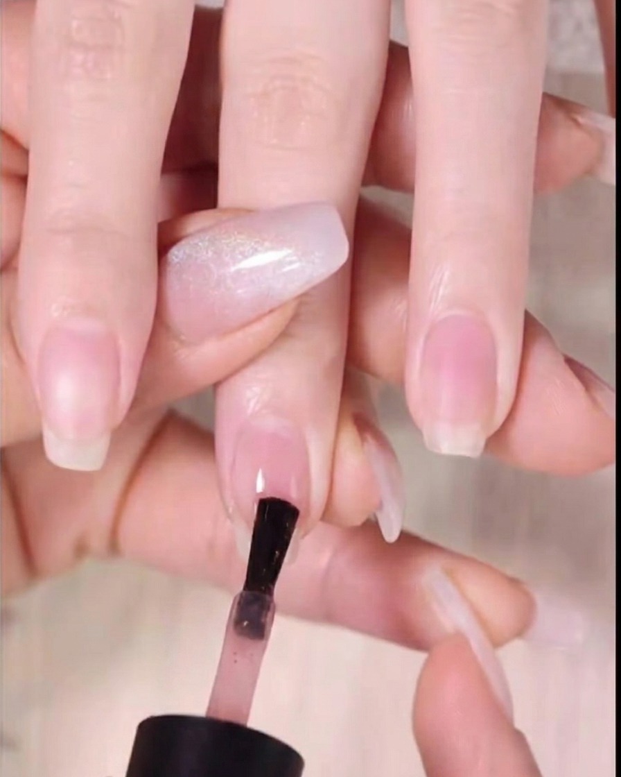 Un pincel aplicando gel color ámbar oscuro en el tercio superior de la punta de la uña.