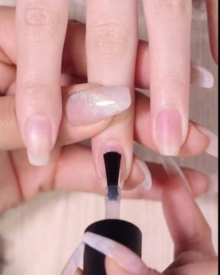 Primer plano de un pincel aplicando gel rojo en los dos tercios superiores de una uña.