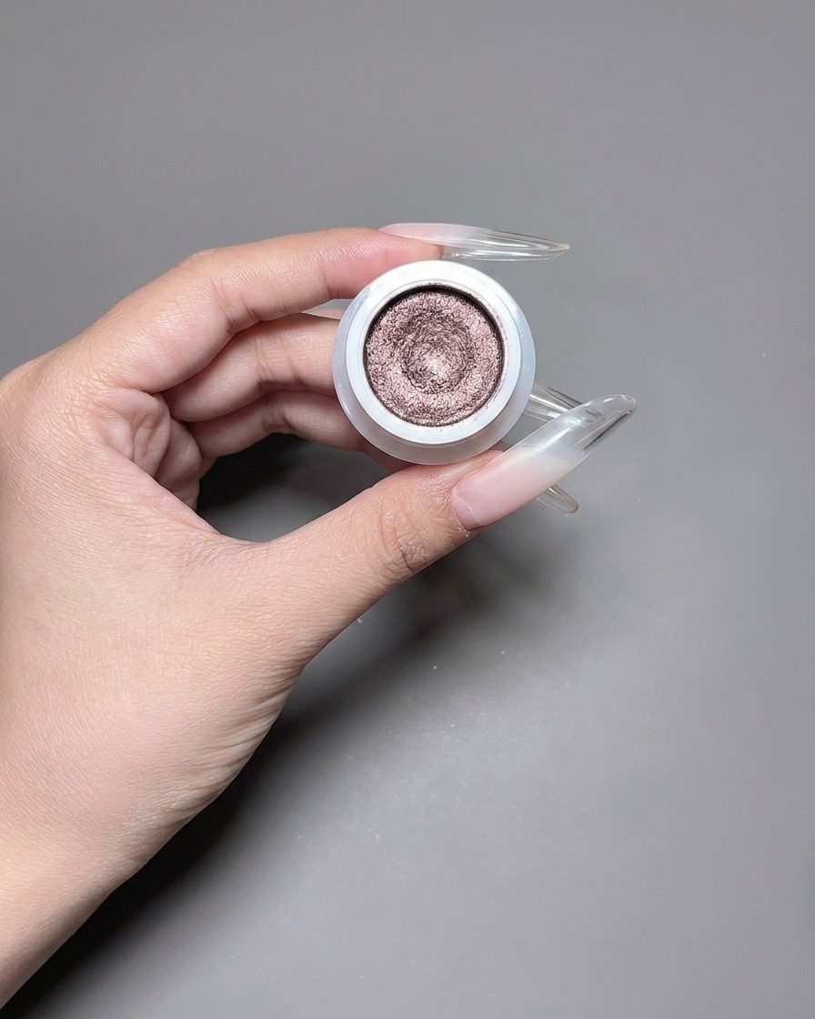 Un pincel aplicando un esmalte en gel ojo de gato reflectante y brillante en una uña larga.