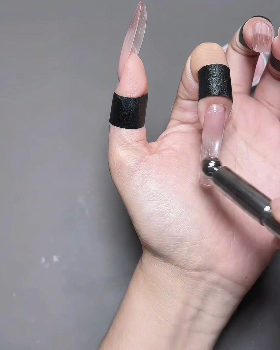 Una mano con uñas de gel ojo de gato colocada dentro de una lámpara de uñas profesional para su curado.
