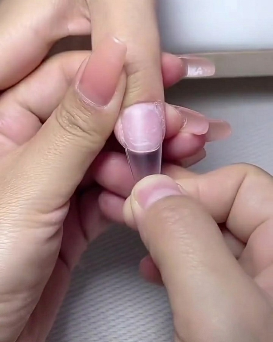 Dedos colocados dentro de una lámpara profesional de uñas UV/LED para el curado.