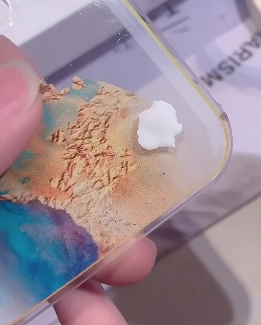 Una pequeña gota de gel de color blanco opaco sobre una paleta de mezcla acrílica transparente.