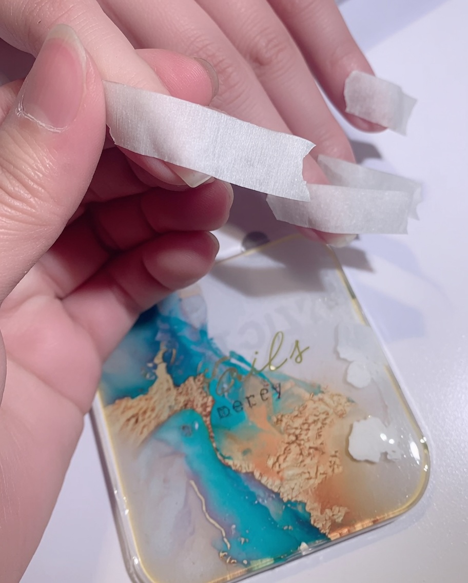 Una esponja dando toques de esmalte de gel blanco sobre la punta de una uña para crear un efecto ombré.