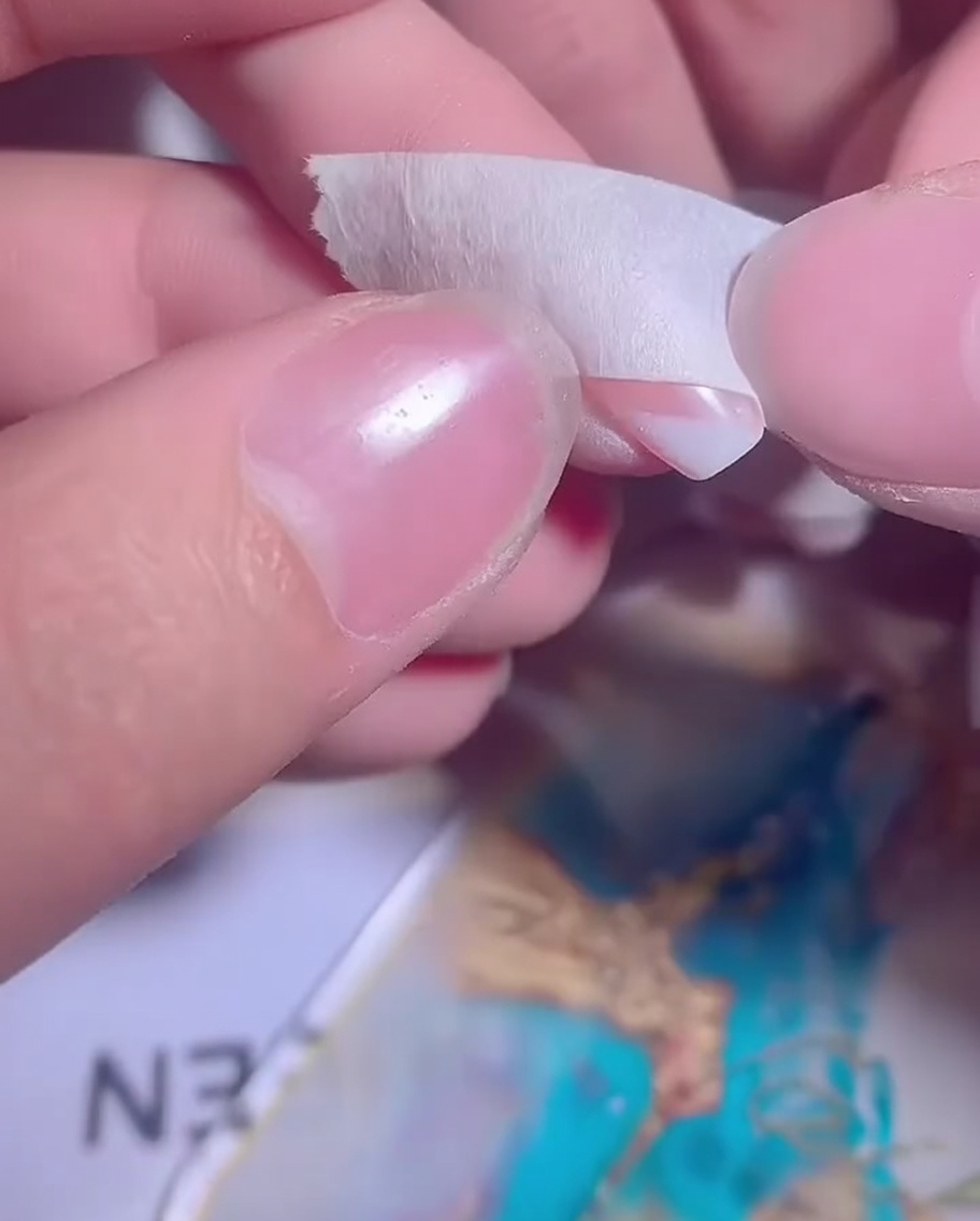 Una uña con un ombré de gel blanco parcialmente aplicado preparándose para una segunda capa.