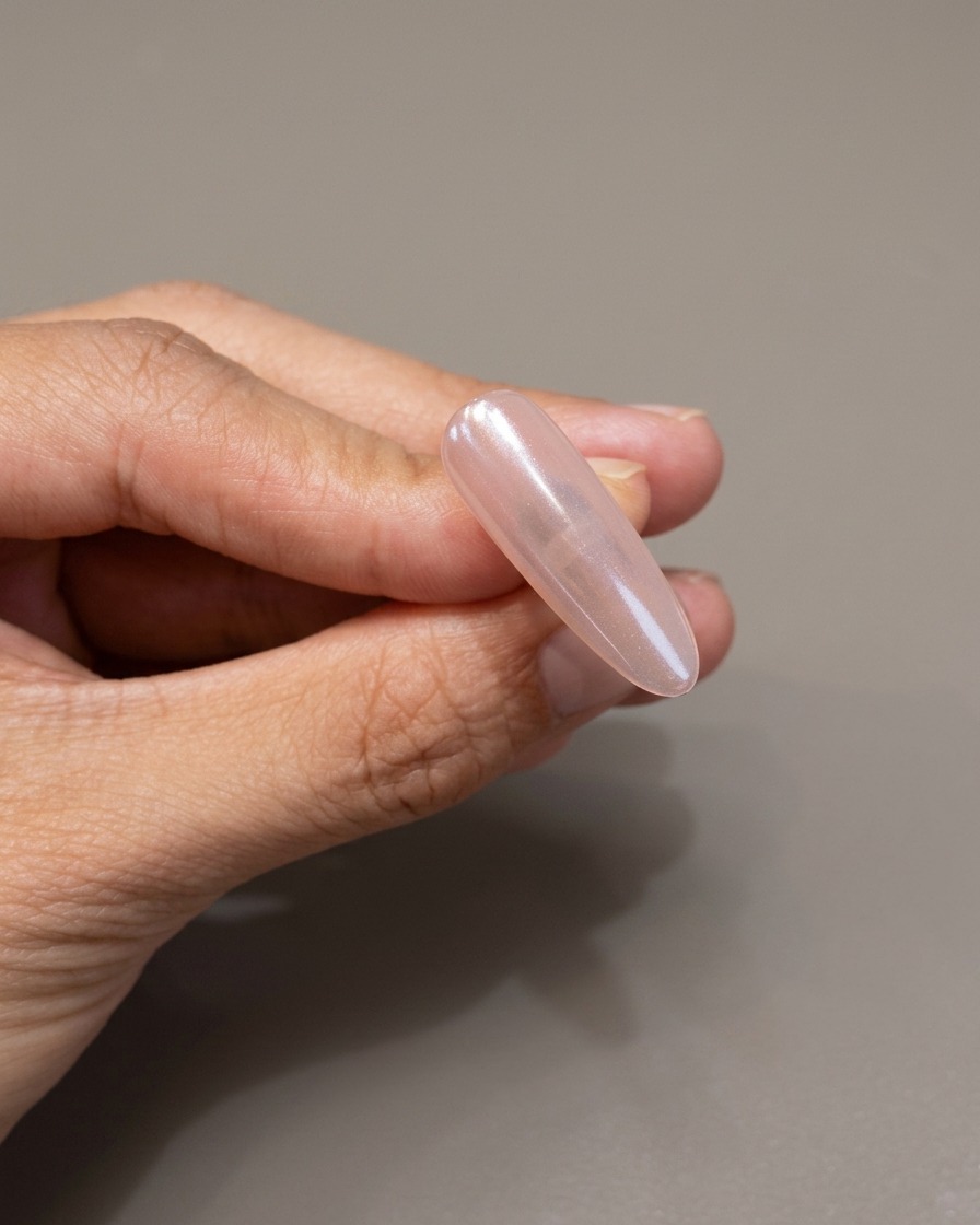 Un pincel aplicando una capa protectora transparente de gel sobre una uña con acabado espejo cromado.