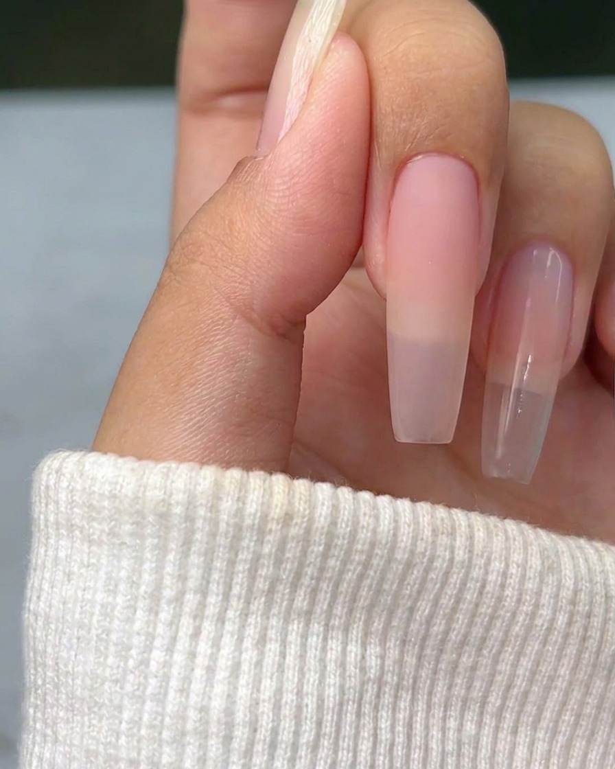 Una cruz delgada de plata metálica pintada sobre la superficie de una uña natural, sirviendo como guía para el diseño posterior.