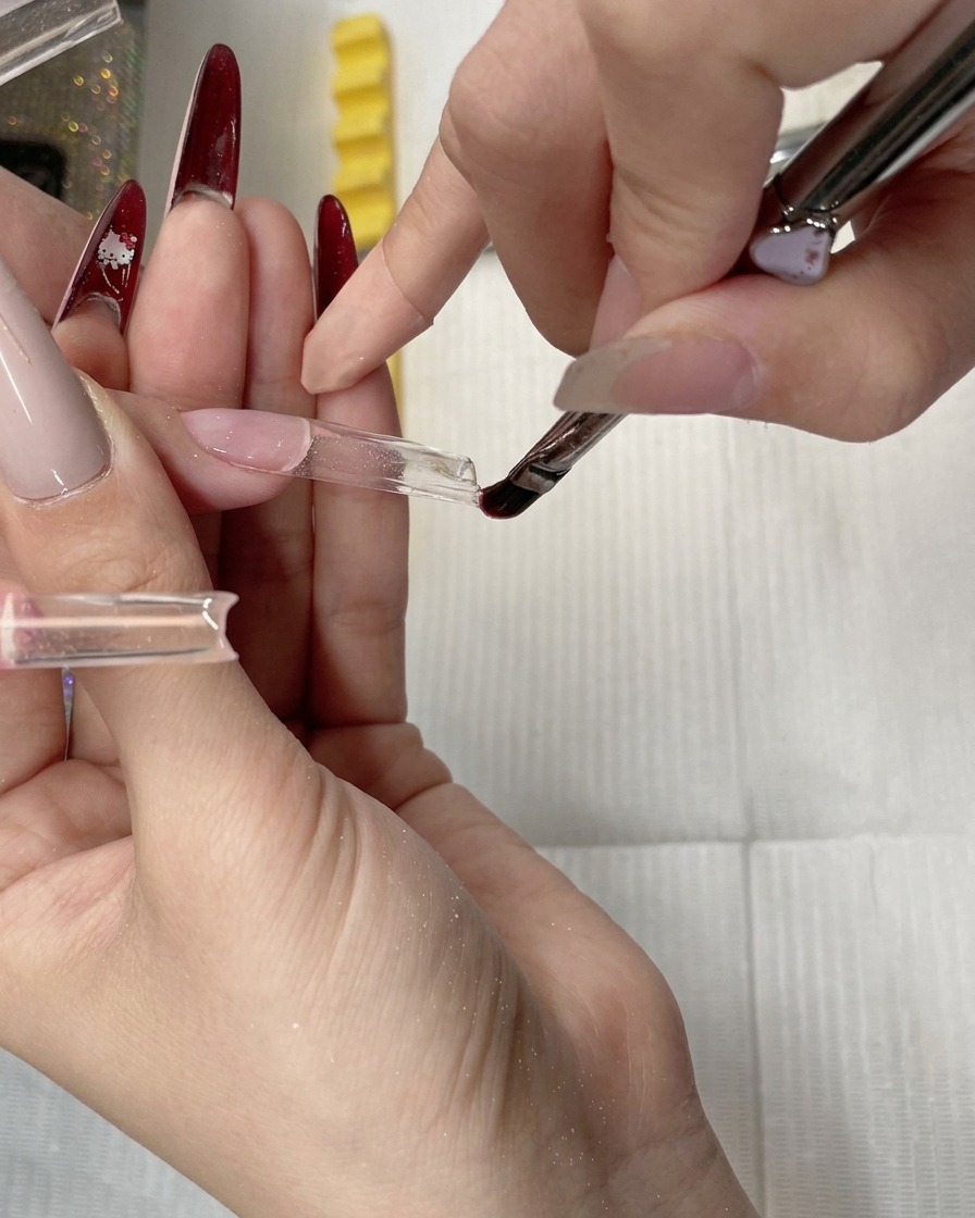 Un pincel de gel suavizando y nivelando gel constructor transparente a lo largo de la punta de una forma.